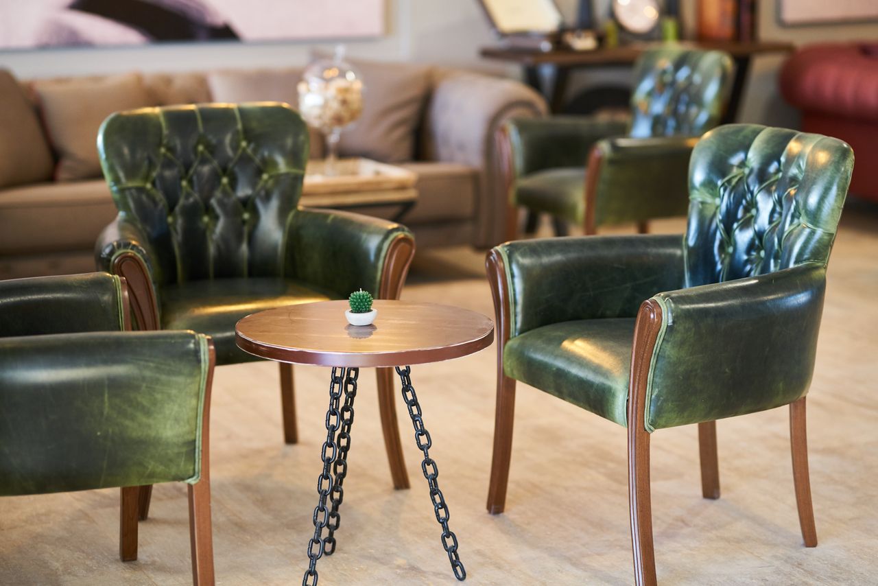 ours-journey Stylish green leather armchairs with a chic table in a contemporary room.