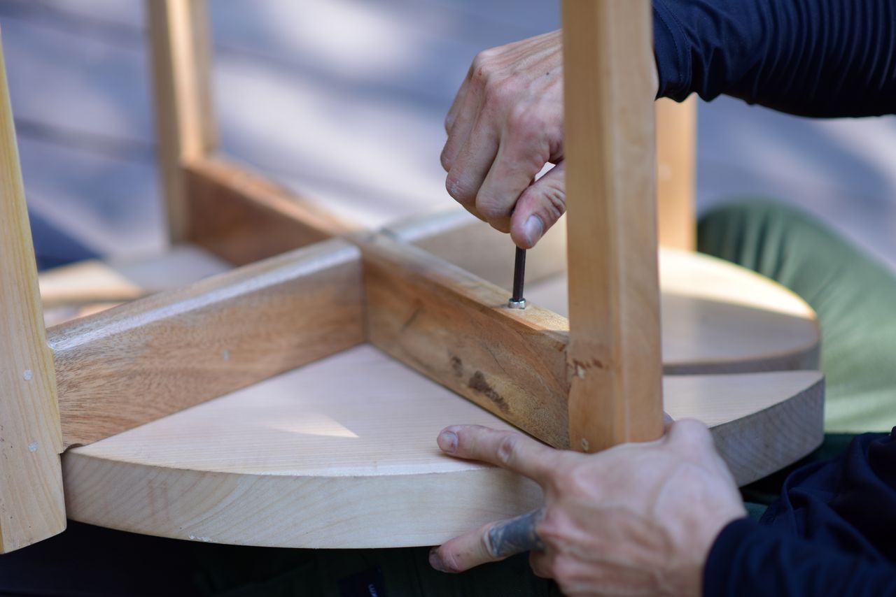 services-03 Hands assembling a wooden stool, highlighting craftsmanship and DIY spirit.