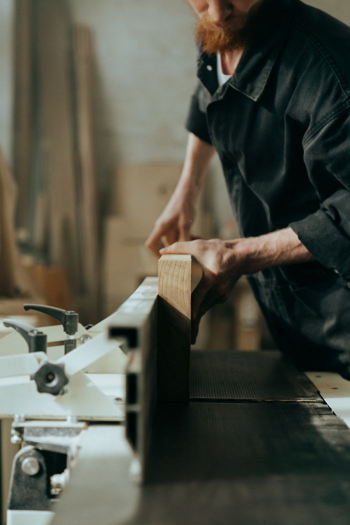 gallery-5 A focused craftsman working on woodworking with a saw in a workshop setting.