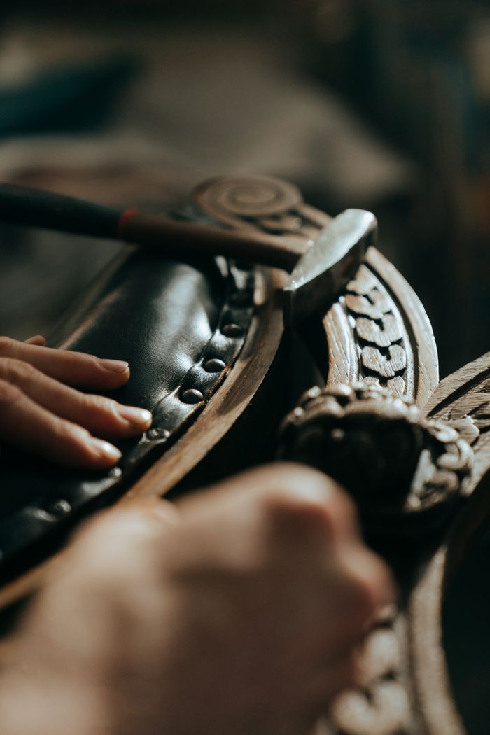 gallery-2 Close-up of skilled hands restoring antique wooden furniture with intricate carvings.