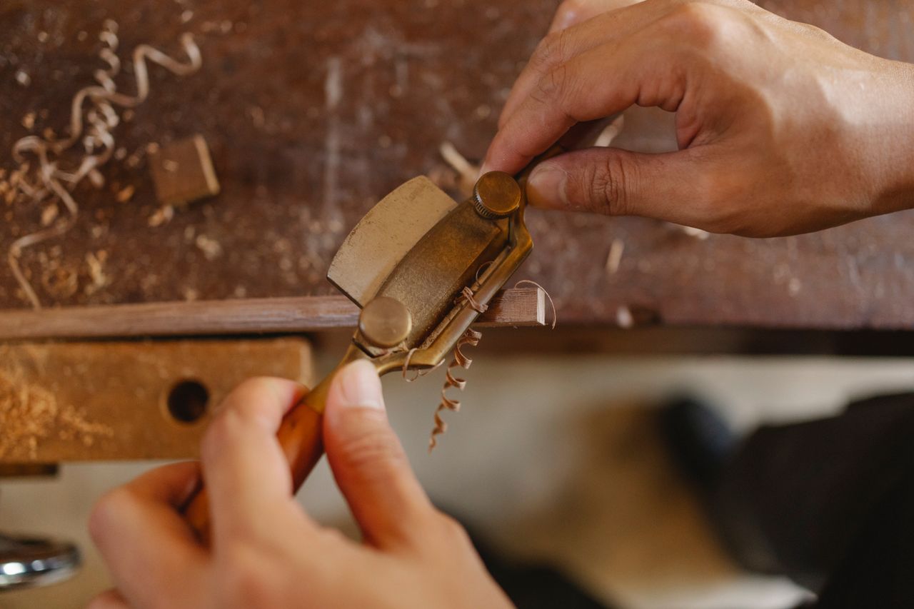 services-img High angle of crop carpenter carving wooden detail with router plane while working at workbench in joinery workshop